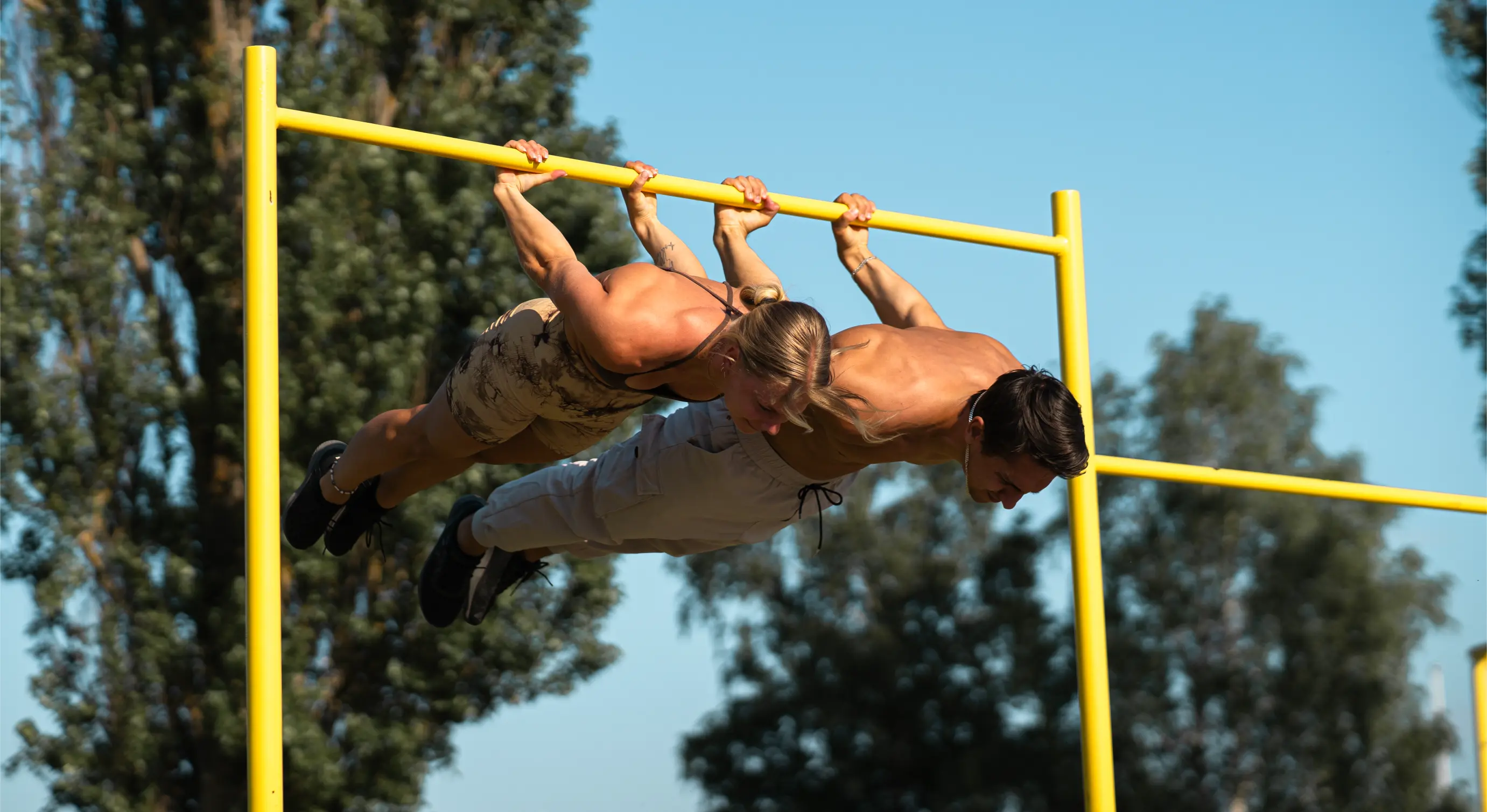 Daniel Flefil och Malin Malle håller front lever sida vid sida på en gul utomhusräck mot blå himmel
