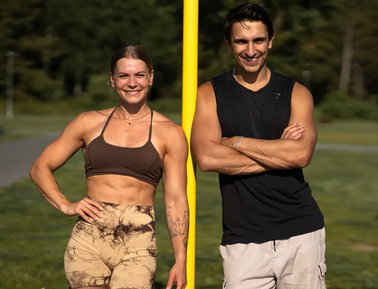 Coachparet Malin Malle och Daniel Flefil står leende bredvid en gul träningsstolpe